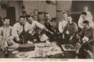 Black and white commercial Japanese postcard showing a group of men around a meal
