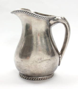 Silver water pitcher with handle, decorative cord design around the spout and base