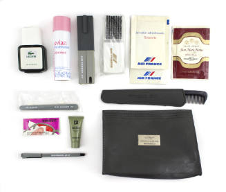 An Air France Concorde toiletry kit, including a black bag with the contents of the bag laid ou…