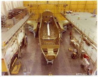 Color photograph of Enterprise mid-body with wings positioned for mating inside warehouse