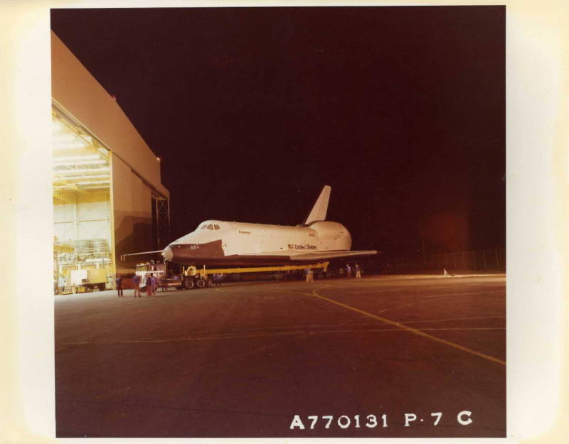 Color photograph of Enterprise final backup and departure from assembly facility