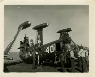 Black and white photograph of a damaged Piasecki HUP-2 Retriever helicopter on USS Intrepid's f…
