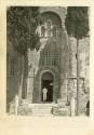 Black and white photograph of an enlisted man walking through a doorway into a stone church 