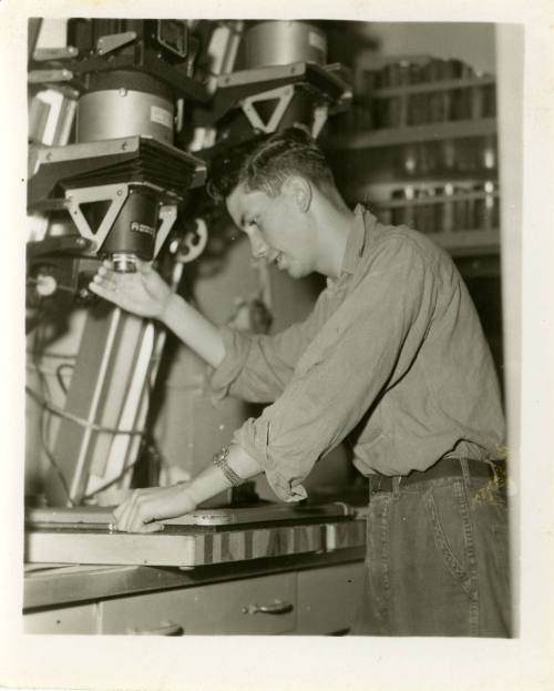 Black and white photograph of a photographer's mate using an enlarger to create prints