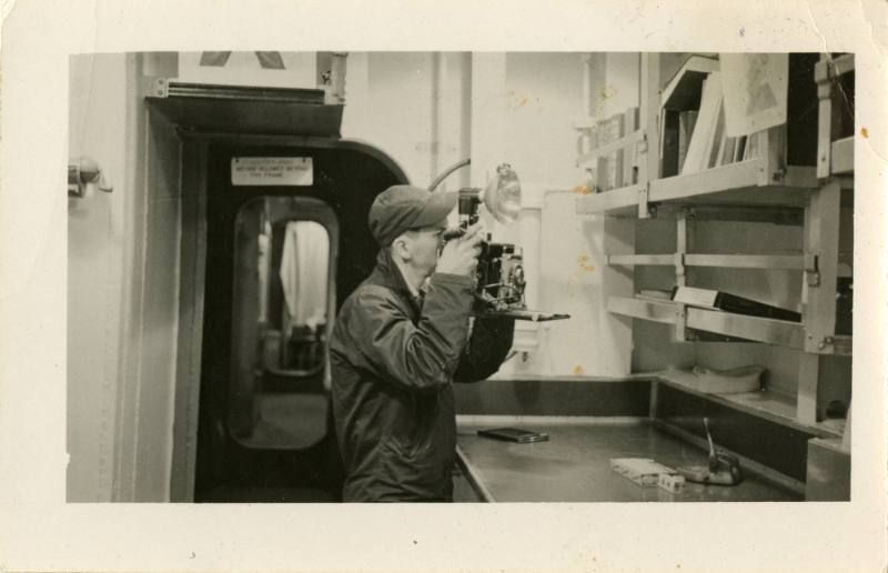 Black and white photograph of a photographer's mate testing a camera inside the photo lab