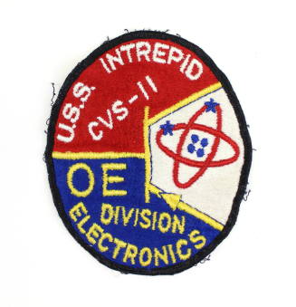 Red and blue oval military patch from USS Intrepid's electronics division, with image of a heli…