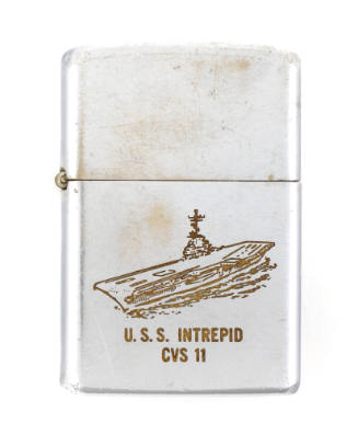 Silver lighter with engraving of the aircraft carrier USS Intrepid at sea, red incription reads…