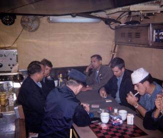 Printed color photograph of men in USS Growler's mess sitting around a table with cigarettes an…