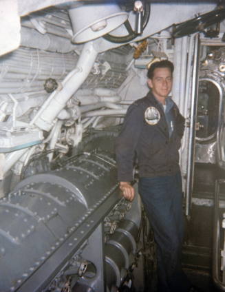 Color photograph of USS Growler's starboard diesel engine with a crew member standing next to i…