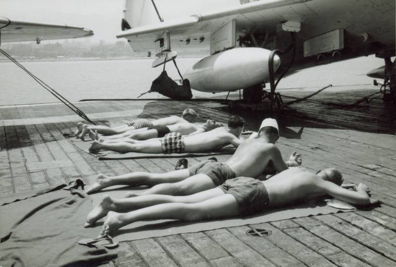 Black and white photograph of men sunbathing on USS Intrepid's flight deck