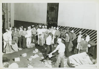 Black and white photograph of sailors waiting on the hangar deck for mail call