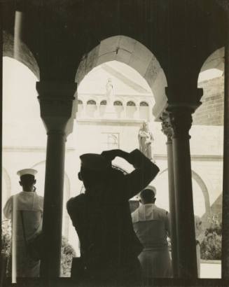 Black and white photograph of a silhouette of a sailor taking a photograph of the exterior of t…