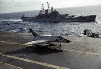Color photograph of Douglas F4D-1 Skyray from VF-162 catching on an arresting cable on Intrepid…