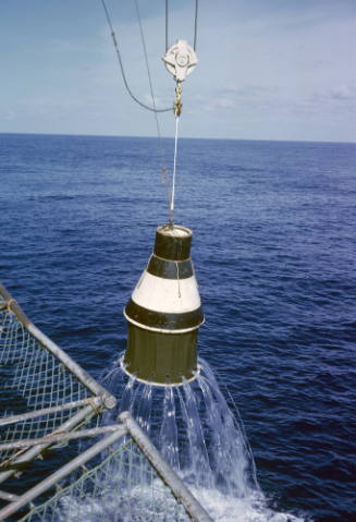 Color photograph of practice space capsule being lifted out of the water