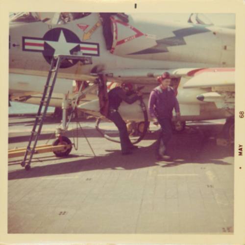 Color photograph of flight deck crew refueling an aircraft