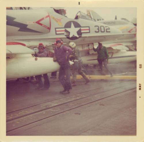 Color photograph of flight deck crew refueling an aircraft