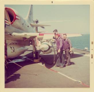 Color photograph of flight deck crew refueling an aircraft