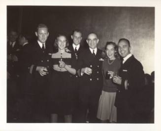 Black and white photograph of four officers and two women with glasses in their hands