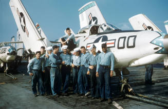 Digital color image of the crew of VA-76 leaning against a Grumman F9F-6 Cougar on the flight d…