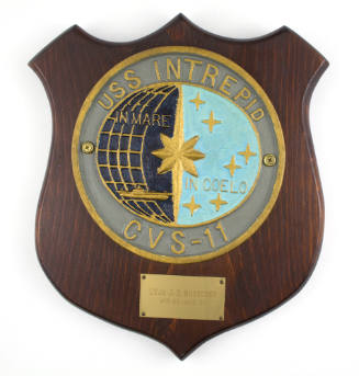 Plaque with colored circular USS Intrepid insignia in the center and brass owner inscription be…