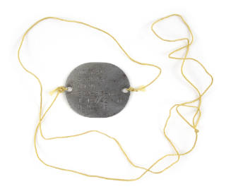 Engraved metal military dog tag encircled by yellow string tied to each end of the tag, inscrip…