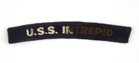 Dark blue U.S. Navy shoulder patch with "USS Intrepid" sewn in white, some letters are stained …