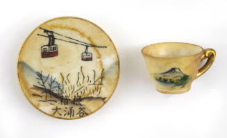 Miniature saucer with painted imagery of cable cars pictured next to a miniature teacup with pa…