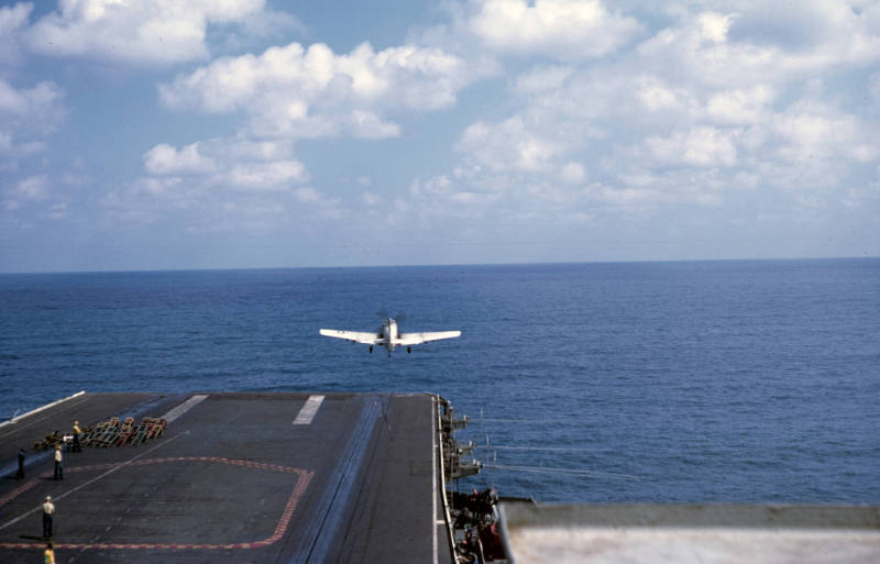 Color slide depicting aircraft taking off from the flight deck with blue water in the backgroun…