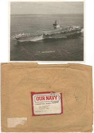 Black and white photo of aircraft carrier USS Enterprise at sea, above a brown envelope with an…