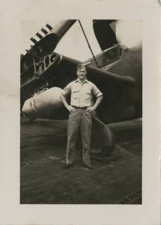 Black and white photograph of an officer standing next to a Curtiss SB2C Helldiver with folded …