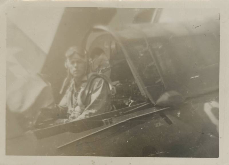 Black and white photograph of a man sitting in the rear gunner seat of a Curtiss SB2C Helldiver…