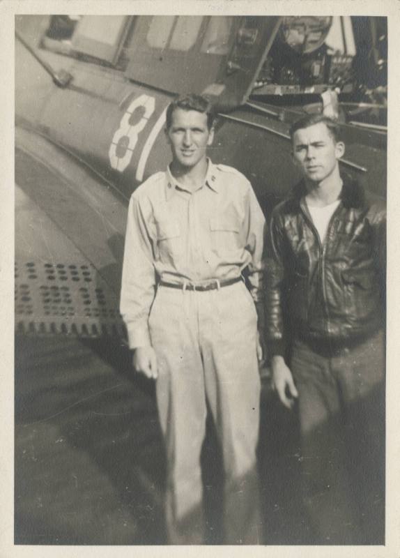 Black and white photograph of two men standing next to the open cockpit of a Curtiss SB2C Helld…