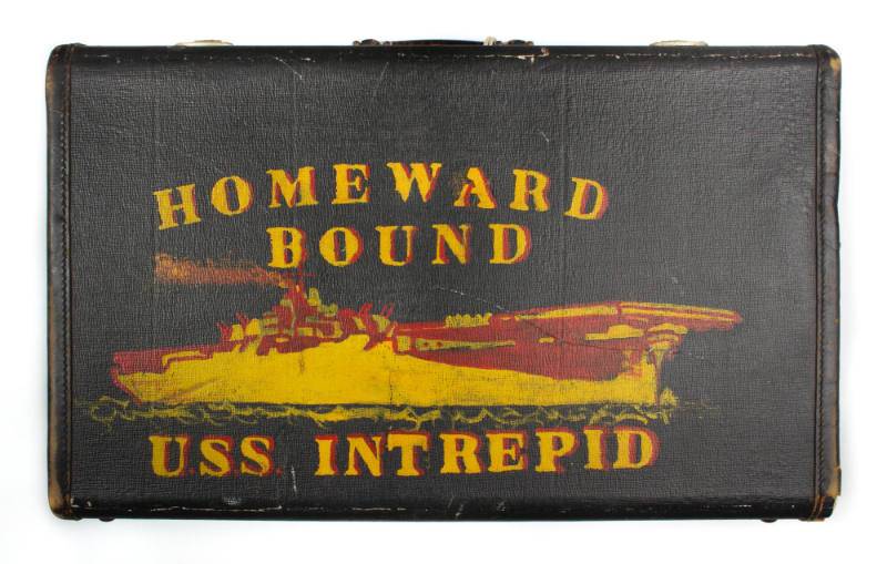 Black suitcase with yellow and red image of aircraft carrier and block lettering that says "Hom…