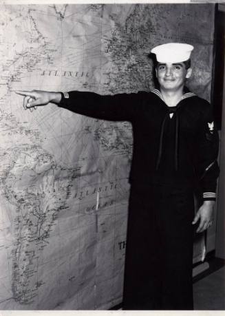 Printed black and white photograph of David Benedict in an enlisted dress blue uniform pointing…