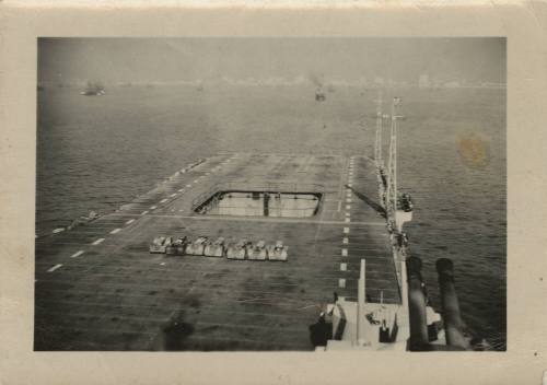 Black and white image looking at the forward section of the flight deck, aircraft tractors park…