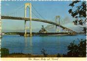 Colored postcard with scalloped edges, image of USS Intrepid passing underneath ta bridge, insc…