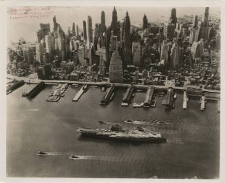 Black and white photograph of USS Intrepid sailing down the East River with small boats on eith…