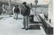 Black and white photograph of an officer standing on a pier next to the submarine USS Growler i…