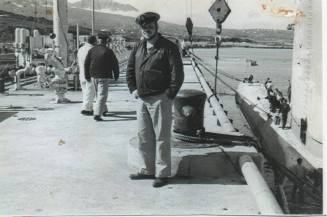 Black and white photograph of an officer standing on a pier next to the submarine USS Growler i…