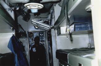 Color photograph of the submarine USS Growler's enlisted berthing compartment, with a sailor in…