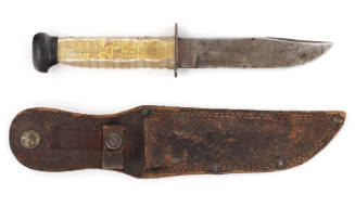 U.S. Navy bowie knife with translucent plastic handle and black pommel facing left, brown leath…