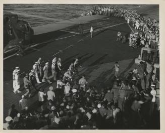 Black and white photograph of astronaut Scott Carpenter walking across USS Intrepid's flight de…
