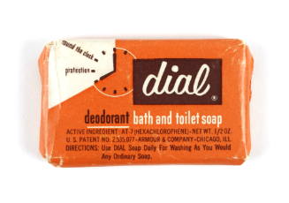 Bar of Dial soap in orange, white and brown wrapping with illustration of a clock and other wri…