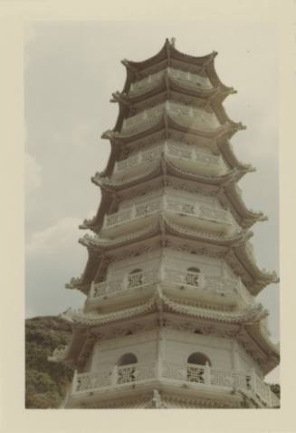 Color photograph of white pagoda tower that is six stories tall, each level has curved decorati…