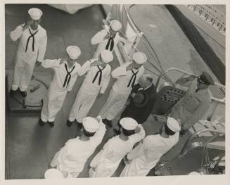 Black and white photograph of sailors saluting two men who are coming on aboard USS Intrepid