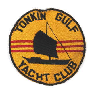 Yellow circular embroidered patch with image of black junk ship in front of three red stripes, …