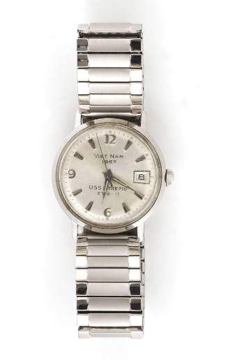Silver wrist watch, text printed on face says “Vietnam 1967 USS Intrepid CVS-11”