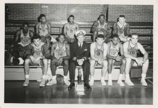 Black and white photograph of USS Intrepid's basketball team in uniform with the ship's captain