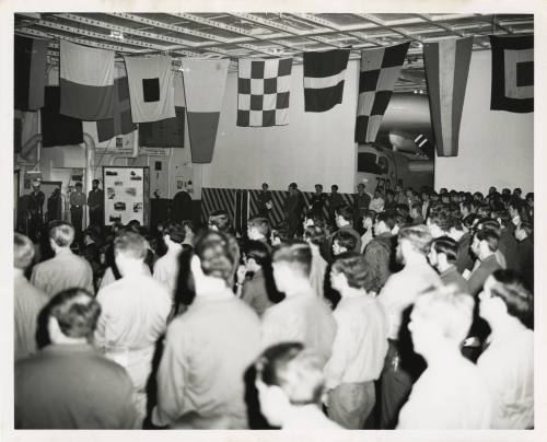 Black and white photograph of a prayer service on USS Intrepid's hangar deck