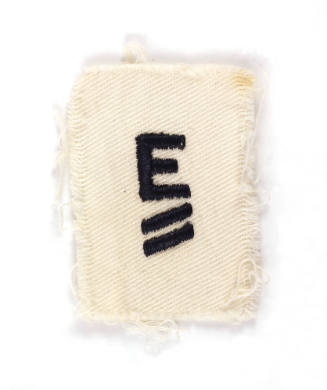 Rectangular white patch with a capital "E" above two hash marks embroidered in navy blue thread